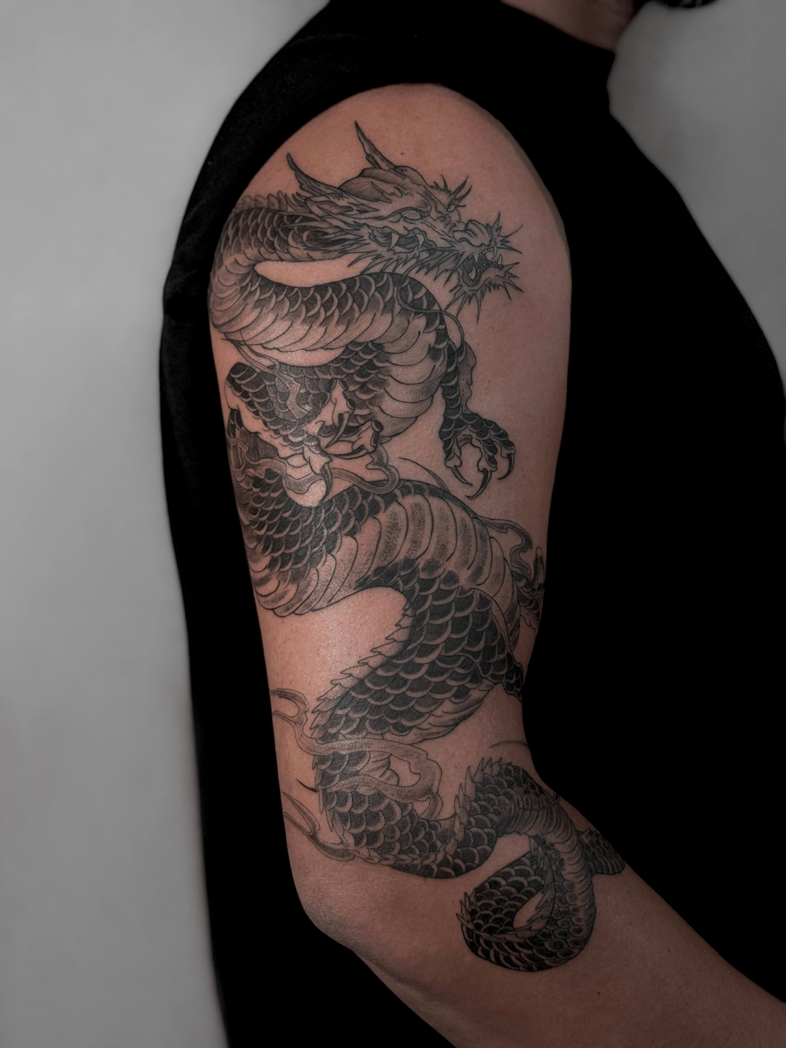 Blackwork tattoo, forearm to shoulder, dragon motif, Valencia