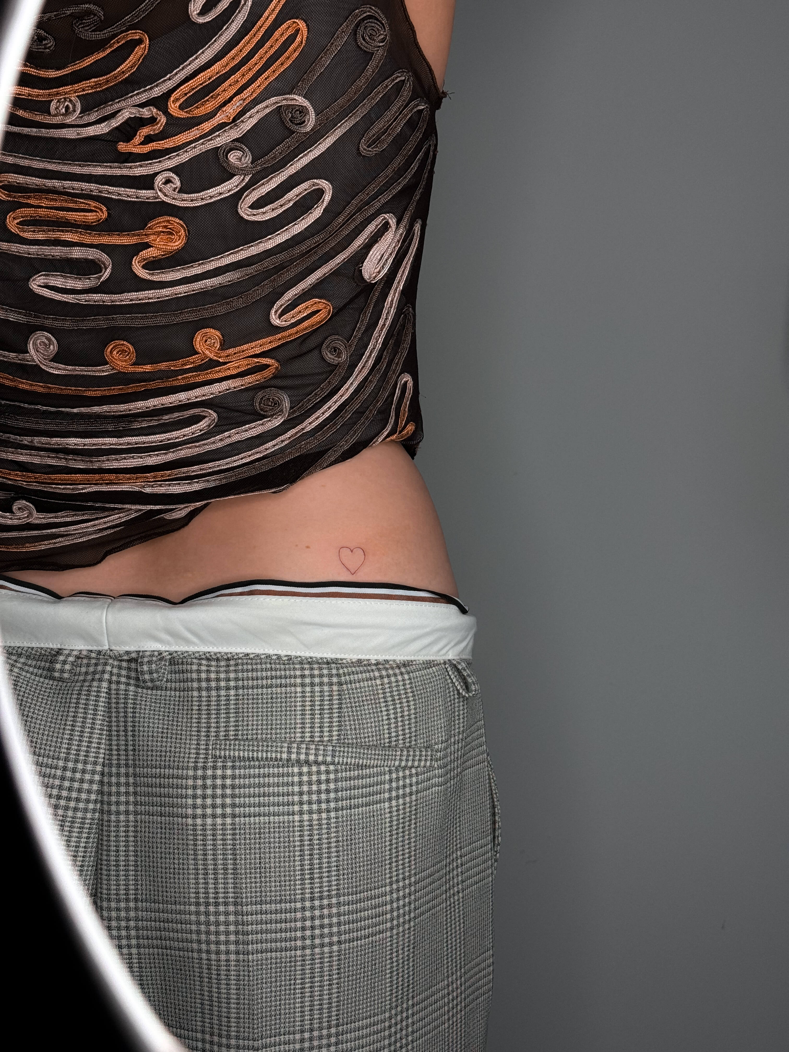 Fine line heart tattoo on the lower back
