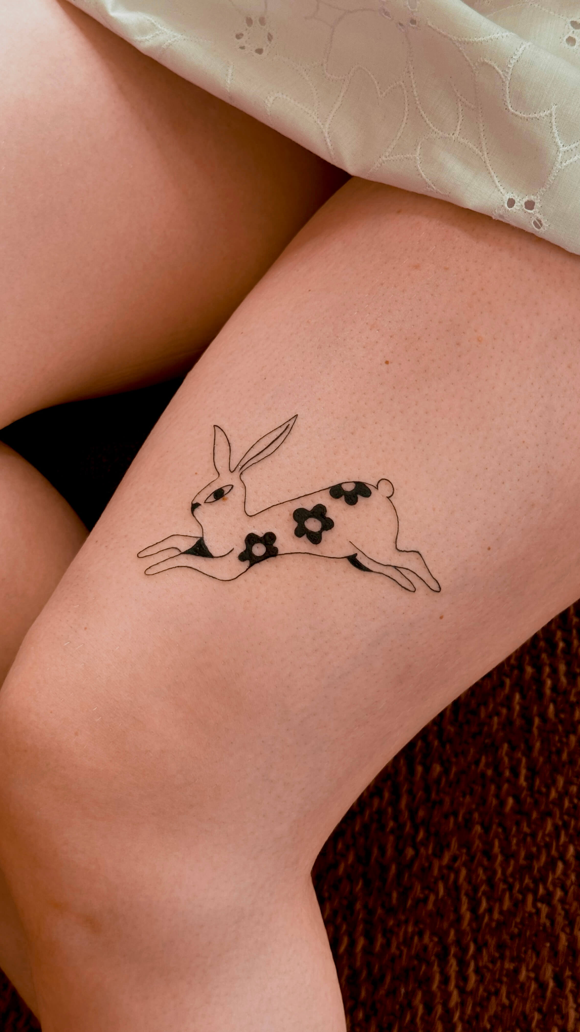 Fine line rabbit tattoo above the knee