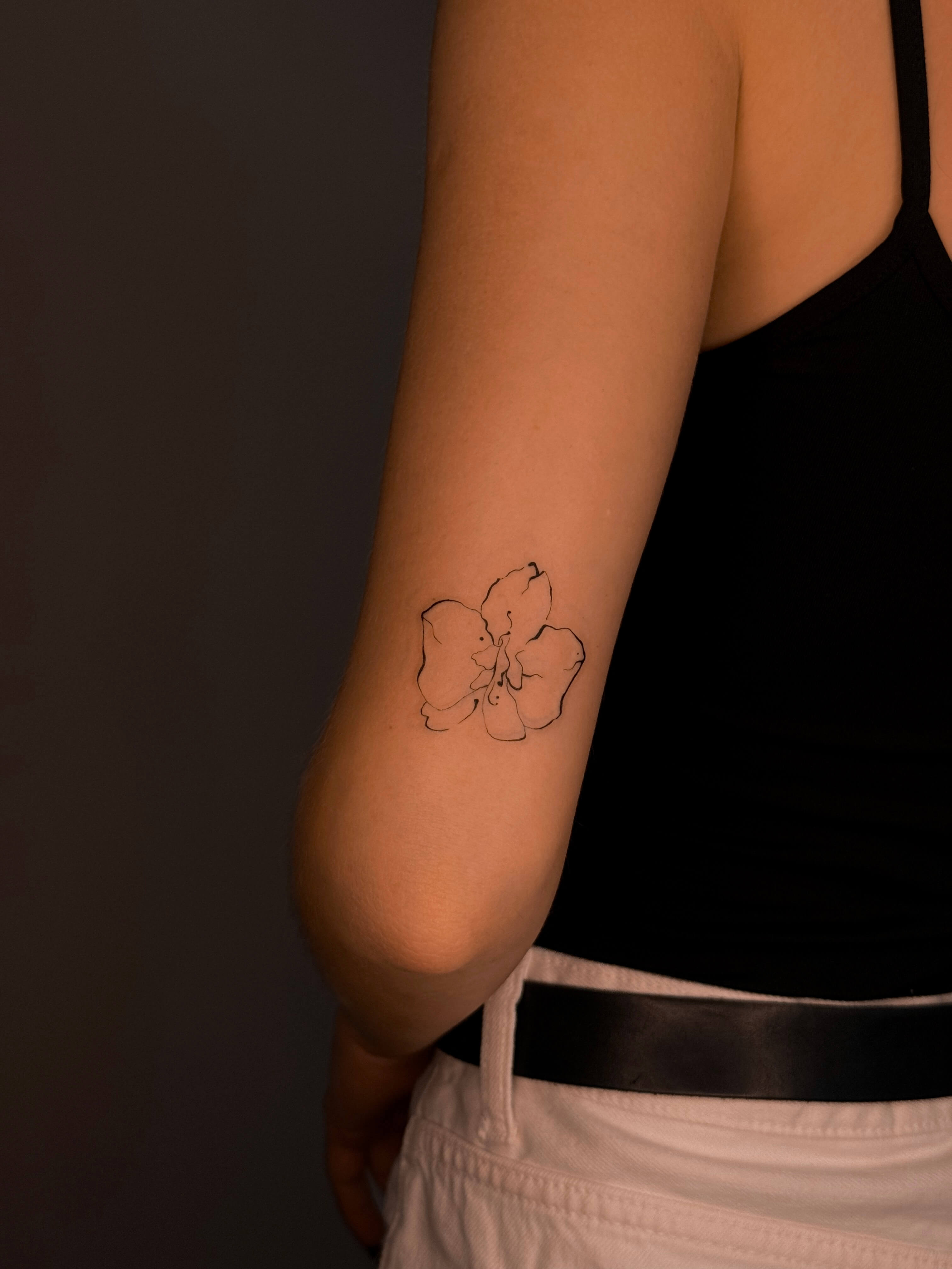 Fine line orchid tattoo on the elbow