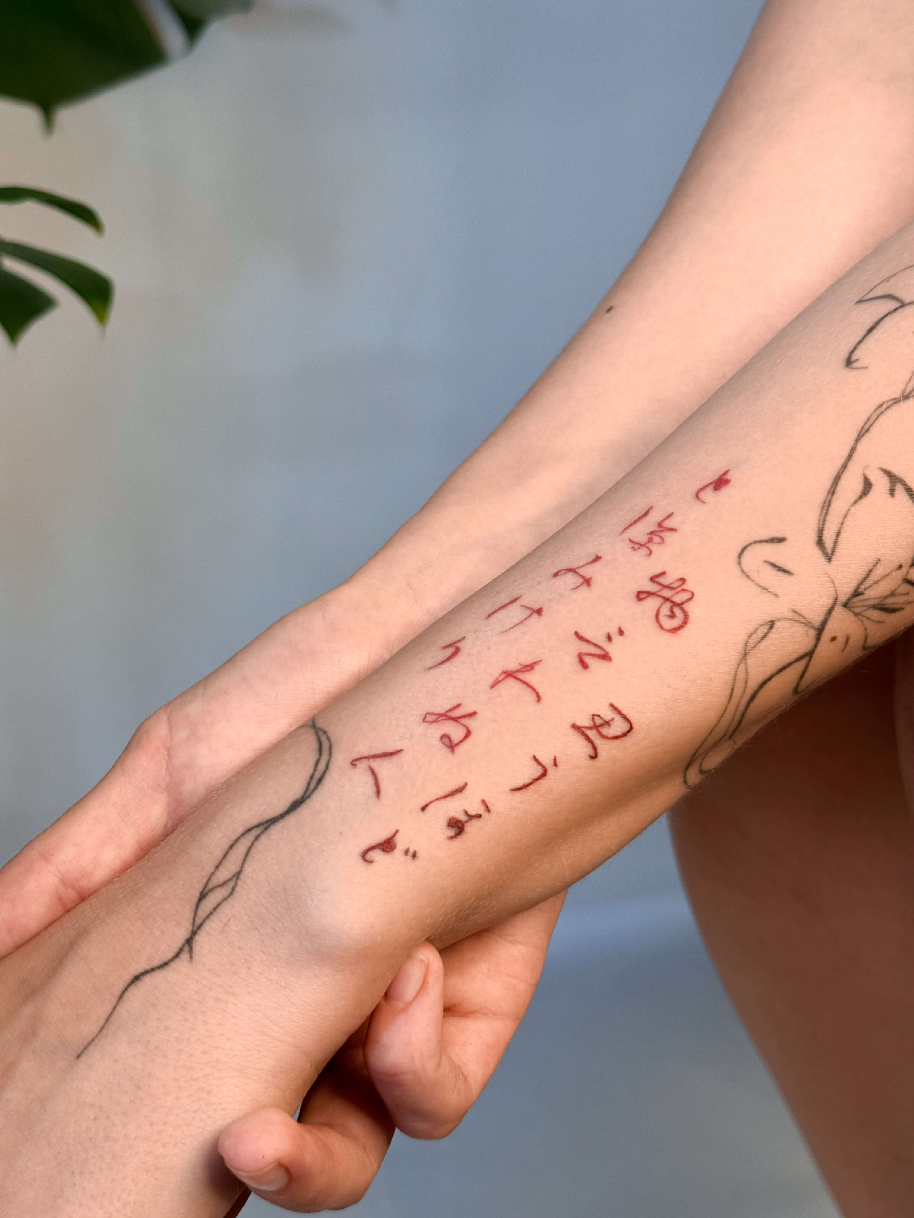 Japanese lettering tattoo in red ink on the forearm