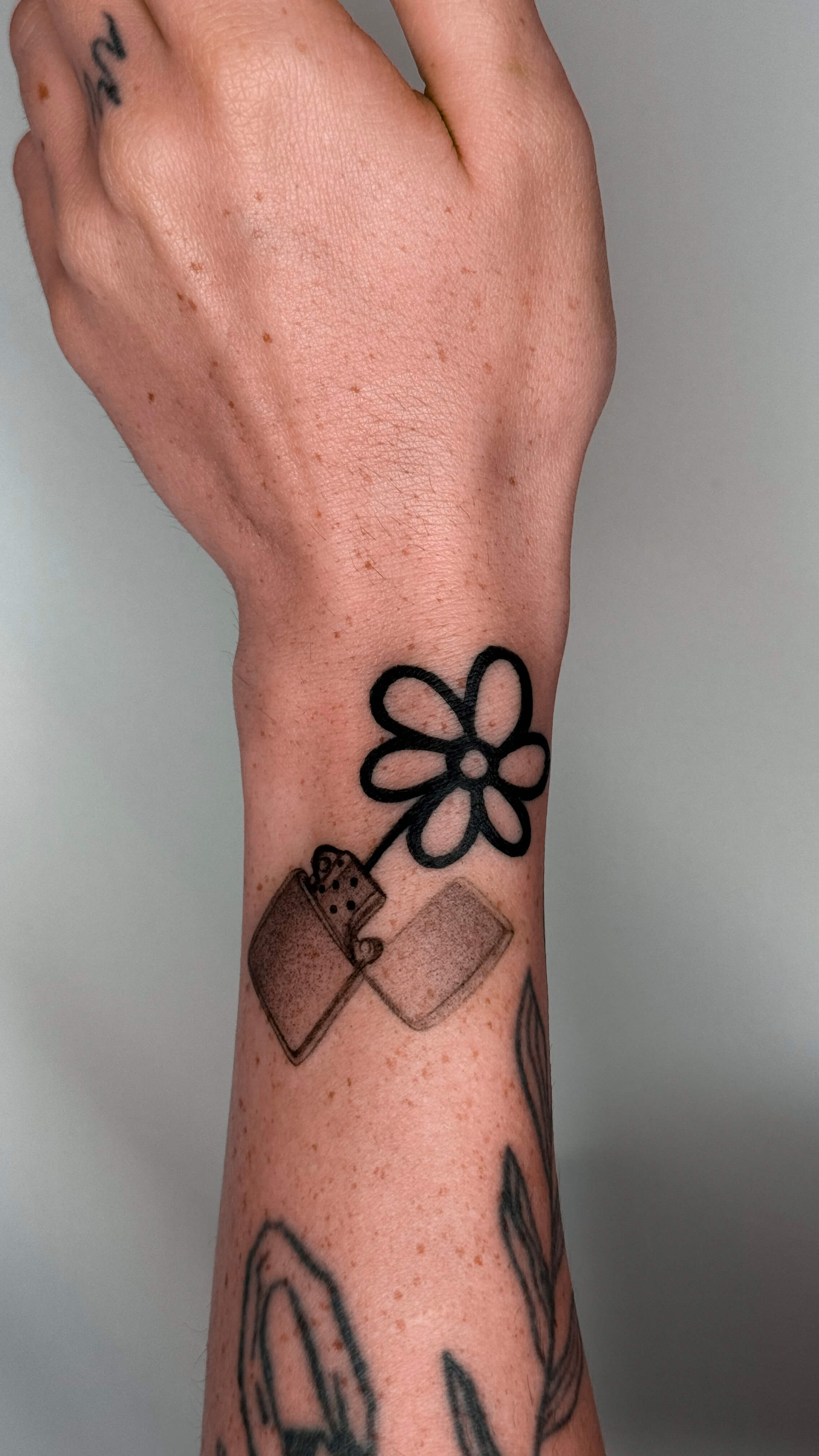 Micro-realism lighter and daisy tattoo